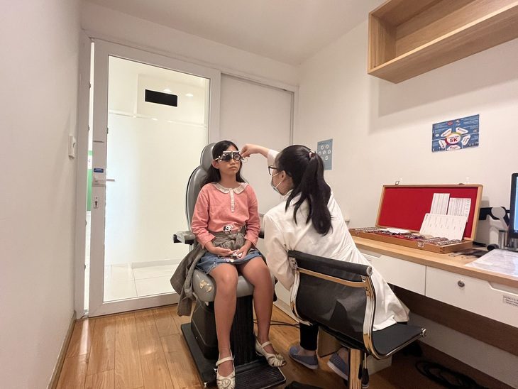 Một em nhỏ bị cận thị được ba mẹ đưa đi đo mắt kính - Ảnh: MỸ DUNG